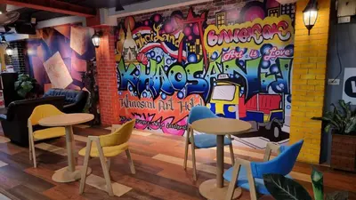 a room with tables and chairs and a wall with graffiti at Khaosan Art Hotel in Bangkok