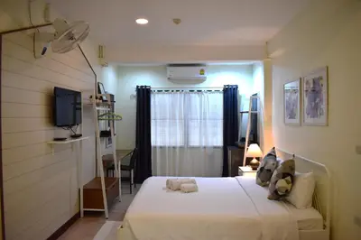 a bedroom with a bed and a desk and a television at Greenery Hostel in Bangkok