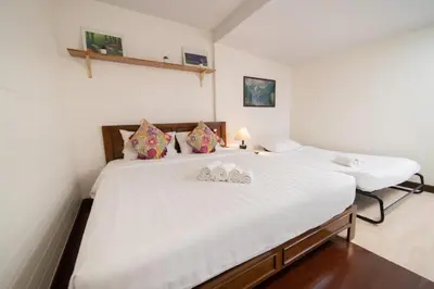 two beds in a room with white sheets and pillows at Greenery Hostel in Bangkok