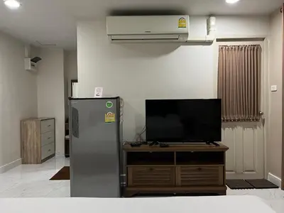 a kitchen with a refrigerator and a flat screen tv at Mall Suites Hotel in Bangkok