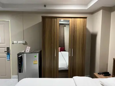 a room with a refrigerator and a bedroom with a bed at Mall Suites Hotel in Bangkok