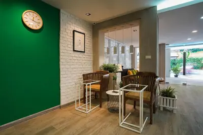 a green wall with chairs and a clock on a wall at Hap@sathorn in Bangkok
