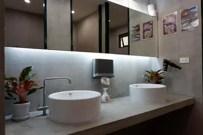 a bathroom with two sinks and a tv on the wall at Peace Factory Hostel in Bangkok