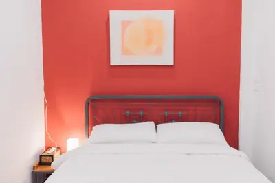 a bedroom with a red wall and a bed at Peace Factory Hostel in Bangkok