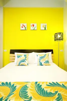 a bedroom with a bed with a yellow wall at Smile Inn in Bangkok