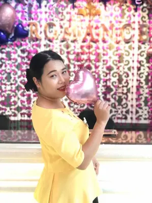 a woman in a yellow dress holding a pink balloon at Romance Hotel Sukhumvit 97 in Bangkok