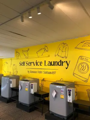 a yellow wall with a sign that reads self service laundry at Romance Hotel Sukhumvit 97 in Bangkok