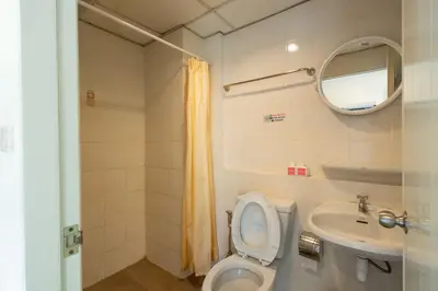 a bathroom with a toilet and a sink and a mirror at Penpark Place in Bangkok
