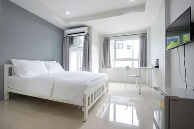 a white bedroom with a white bed and a television at NW Apartment Lasalle 59 in Bangna