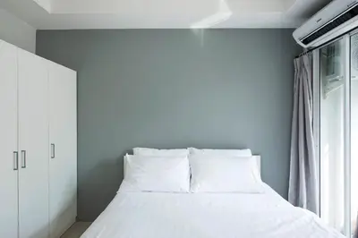 a bedroom with a bed with white sheets and a window at NW Apartment Lasalle 59 in Bangna