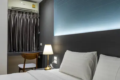 a bedroom with a bed and a chair and a window at Siam Star Hotel in Bangkok