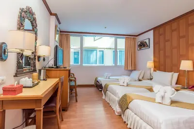 a hotel room with three beds and a desk at New Siam Riverside in Bangkok