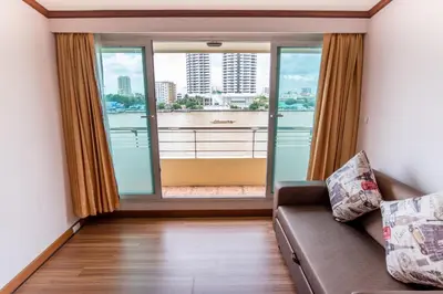 a living room with a couch and a large window at New Siam Riverside in Bangkok