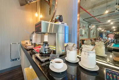a kitchen with a counter with cups and a coffee maker at Qiu Hotel Sukhumvit - BTS On Nut Station in Bangkok