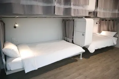 two beds in a small room with white sheets at Bedspread Hostel in Bangkok