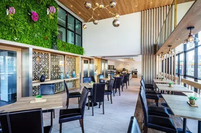 a restaurant with tables and chairs and plants at Narra Hotel in Bangkok
