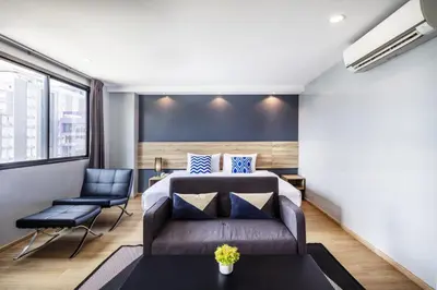 a bedroom with a bed and a couch and a table at Narra Hotel in Bangkok