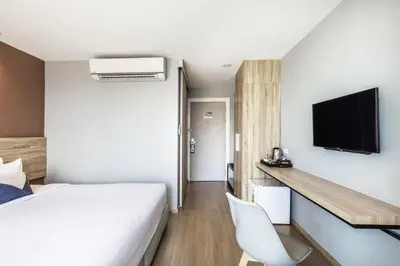 a bedroom with a bed and a tv on a wall at Narra Hotel in Bangkok