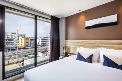 a bedroom with a large bed and a large window at Narra Hotel in Bangkok
