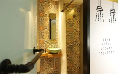 a bathroom with a mirror and a bowl on a shelf at Nandha Hotel in Bangkok