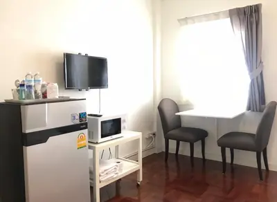 a small room with a microwave and a table with two chairs at 12/14 HOME Studio in Bangkok