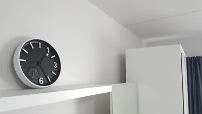 a black clock on a white shelf in a room at Popular Condo C5 IMPACT in Pak Kret
