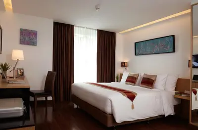 a hotel room with a bed and a desk and a window at Citypoint Hotel in Bangkok