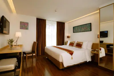 a hotel room with a bed and a desk and a mirror at Citypoint Hotel in Bangkok