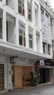 a white building with a balcony on a street at Pinto Hostel in Bangkok