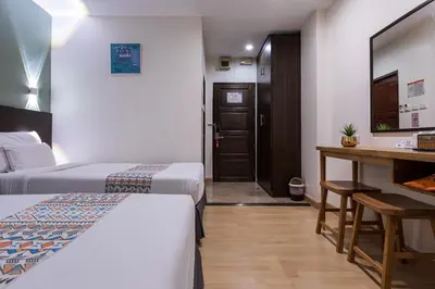 a hotel room with two beds and a desk at 24@Home Hotel in Nonthaburi