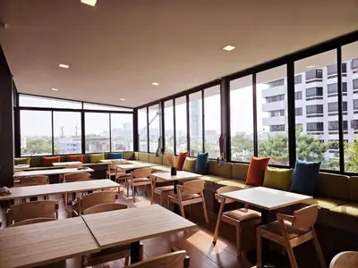 a restaurant with tables and chairs and windows at Red Door Samsen Hotel, Bangkok in Bangkok