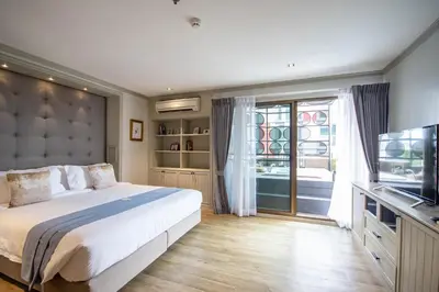 a bedroom with a large bed and a television at THEA Private Suites by TH District in Bangkok