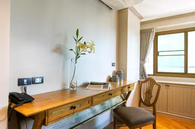 a room with a wooden desk with a phone and a chair at THEA Private Suites by TH District in Bangkok