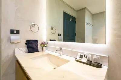 a bathroom with a sink and a large mirror at THEA Private Suites by TH District in Bangkok