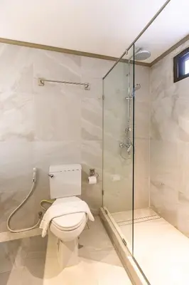 a bathroom with a toilet and a glass shower at THEA Private Suites by TH District in Bangkok