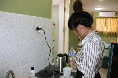 a woman standing in a kitchen holding a bottle of water at Bann In Suan in Ban Lat Tanot