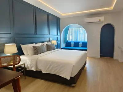 a bedroom with a large bed with a blue wall at Regent Ramkhamhaeng 22 in Bangkok