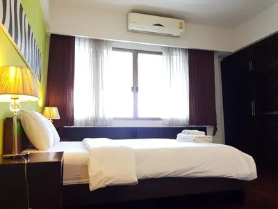 a bedroom with a large bed and a window at P.T. Court in Bangkok