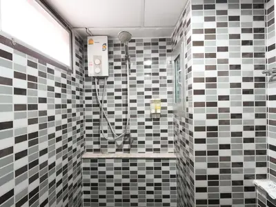 a bathroom with a shower with black and white tiles at Regent Ngamwongwan Hotel in Nonthaburi