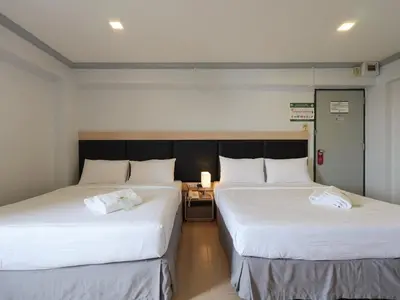 two beds in a room with white sheets at Regent Ngamwongwan Hotel in Nonthaburi