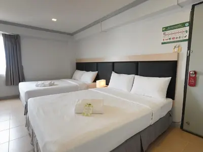 two beds in a hotel room with white sheets at Regent Ngamwongwan Hotel in Nonthaburi