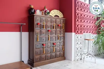 a wooden cabinet in a room with a red wall at Talakkia Boutique Hotel in Bangkok
