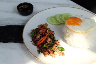 a white plate of food with rice and an egg at Talakkia Boutique Hotel in Bangkok