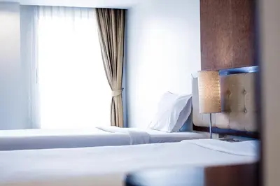two beds in a hotel room with a window at Romance Hotel Bangna in Bangkok