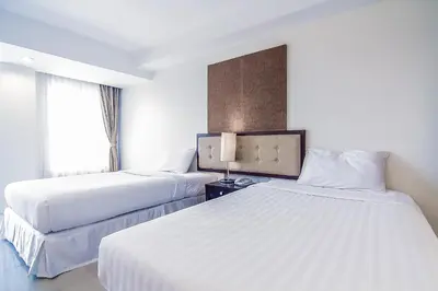 a hotel room with two beds and a window at Romance Hotel Bangna in Bangkok