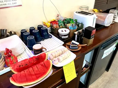 a counter with two plates of watermelons and other foods at Luck Yimm Hostel in Bangkok