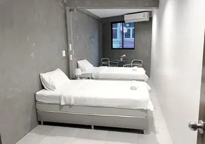 two beds in a hospital room with a window at Luck Yimm Hostel in Bangkok