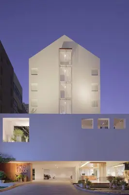 two pictures of a white building with lights on at twothree a homely hotel - SHA Extra Plus in Bangkok