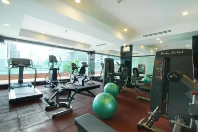 a gym with treadmills and exercise equipment in a building at Amora NeoLuxe Suites Hotel in Bangkok