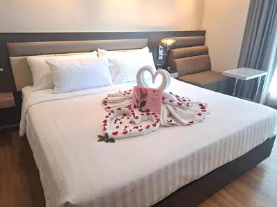 a bed with two wedding towels on it at Amora NeoLuxe Suites Hotel in Bangkok